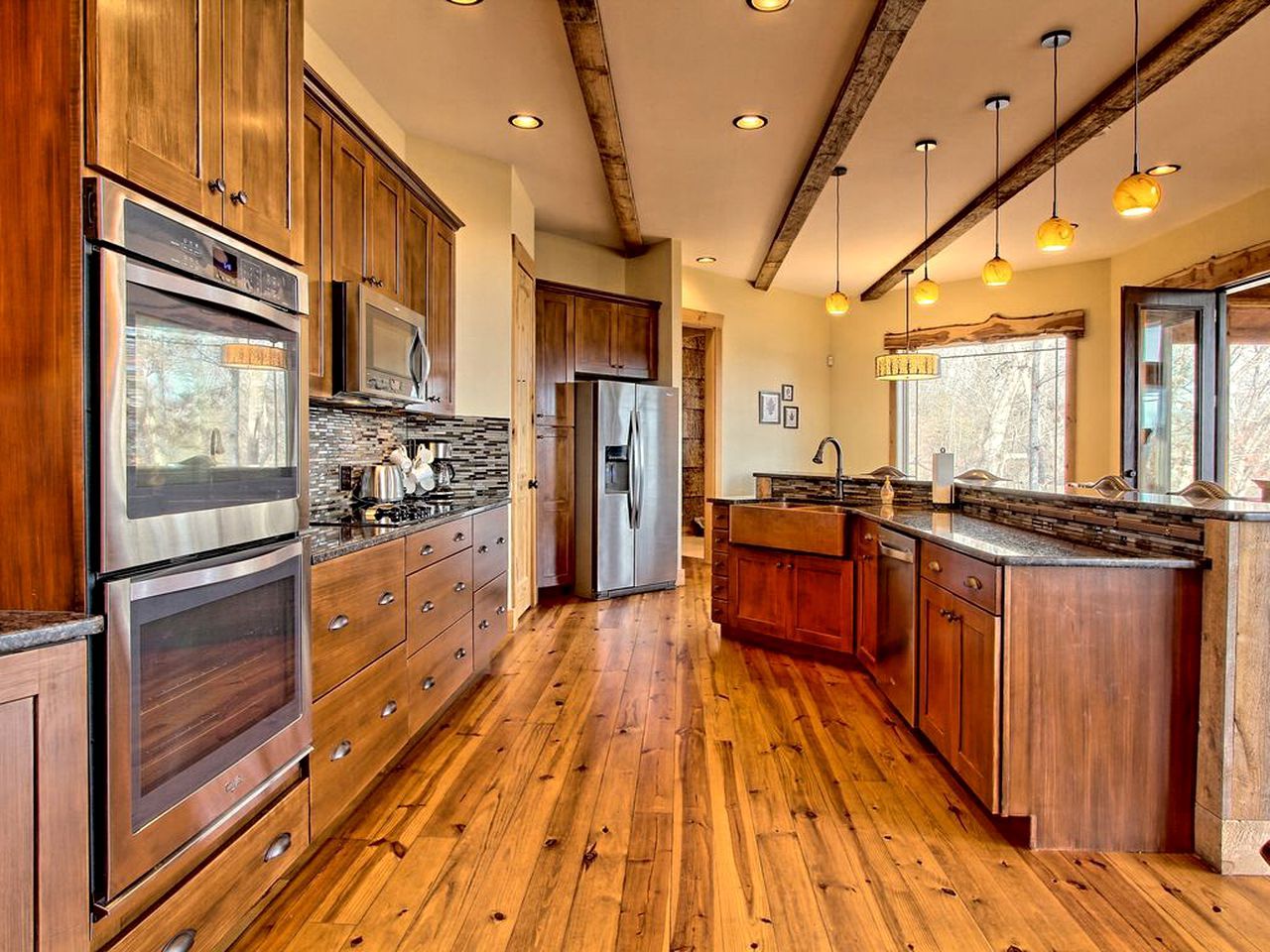 A kitchen with wooden cabinets, stainless steel appliances, and a wooden floor.