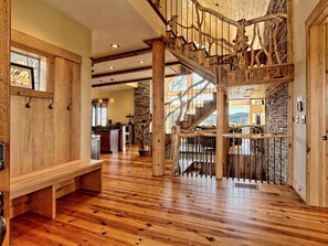 A spacious interior with a wooden staircase, a stone wall, and a wooden bench. - Beautiful, Luxury Cabin with Out-Door Hot Tub near Lake Burton in Northern Georgia (Clayton)