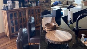 A kitchen with a coffee bar, stone wall, wooden furniture, and a certificate on the counter.