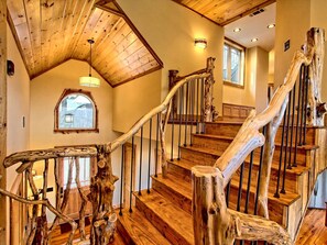 A wooden staircase with a rustic design, a skylight, and a window with a view.