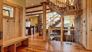 A spacious interior with a wooden staircase, a stone wall, and a wooden bench.