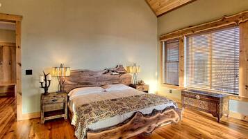 A bedroom with a wooden bed, two bedside tables with lamps, a wooden headboard, and a window with blinds.