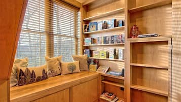 Un rincón acogedor para leer con un banco empotrado, estanterías de madera y una ventana con persianas.