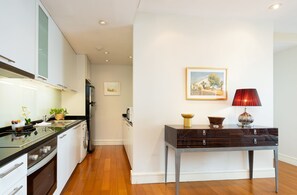 A modern kitchen with a dishwasher, oven, and a table with a lamp and a bowl. - 2 Bed Serviced Modern Oriental SkyVilla (Krung Thep Maha Nakhon)