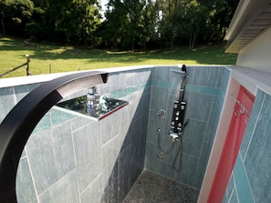 A small, enclosed outdoor shower with a glass enclosure, a metal faucet, and a handheld showerhead. - Modern Cottage Rental on a Peaceful Farm near Amish Country in Pennsylvania (Columbia)