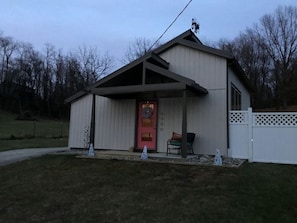 A single-story building with a red door, a covered porch, and a white fence. - Modern Cottage Rental on a Peaceful Farm near Amish Country in Pennsylvania (Columbia)