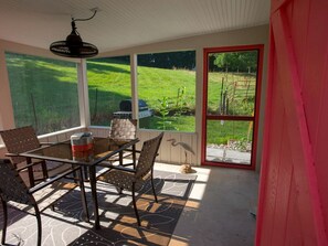 Une terrasse couverte avec une table en verre, des chaises et une statue d’oiseau.