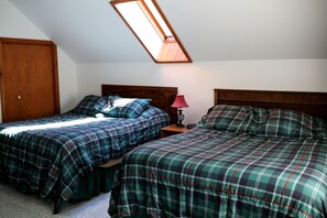 A bedroom with two beds, a skylight, a wooden door, and a nightstand with a lamp. - Lakefront Cabin Rental with a Paddle Boat near Wisconsin Dells, Wisconsin (Tomah)