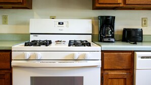 Eine Küche mit einem weißen Herd, einer Kaffeemaschine und einem Toaster auf der Arbeitsfläche.