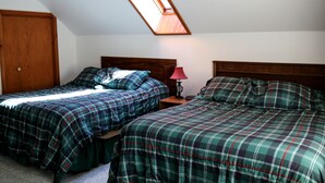 Ein Schlafzimmer mit zwei Betten, einem Oberlicht, einer Holztür und einem Nachttisch mit Lampe.