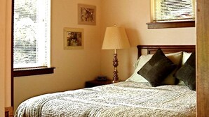 Et soveværelse med en seng, et natbord, en lampe og tre billeder i rammer på væggen.