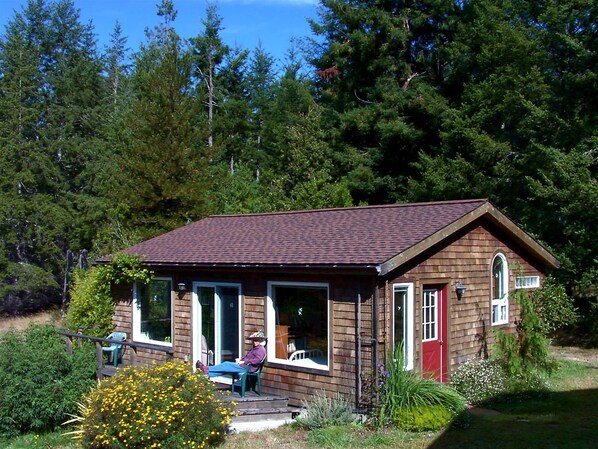 Une petite cabane en bois avec une véranda, une seule fenêtre et une porte.