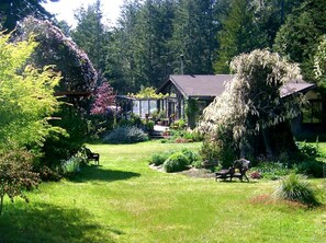 Ein Haus, umgeben von einem gepflegten Garten mit Bänken und einem kleinen Gartenhaus.