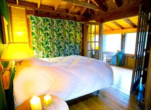 Ein Schlafzimmer mit einem großen Bett, einer Wand mit grünem Muster und einem Fenster mit Tageslicht.