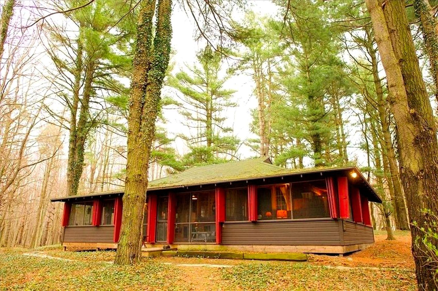Une cabane dotée d’un toit en pente, de grandes fenêtres et d’une terrasse en bois.