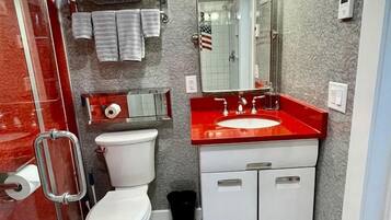 A bathroom with a toilet, sink, mirror, towel rack, and a patterned floor.