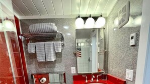 Un baño con inodoro, lavabo, espejo, toallero y piso estampado.