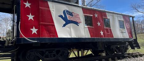 A stationary train car with a red and white color scheme, stars, and an eagle emblem.