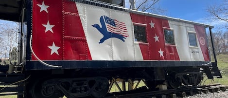 A stationary train car with a red and white color scheme, stars, and an eagle emblem.