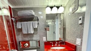 Un baño con inodoro, lavabo, espejo, toallero y piso estampado.