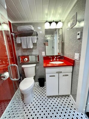 Une salle de bain comprenant des toilettes, un lavabo, un miroir, un porte-serviettes et un carrelage décoratif.