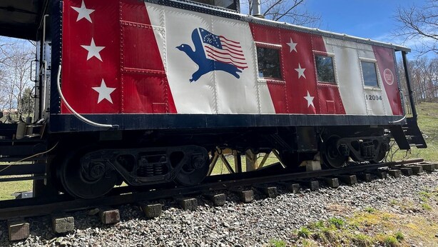 Un vagón de tren estacionado con un esquema de color rojo y blanco, estrellas y el emblema de un águila.