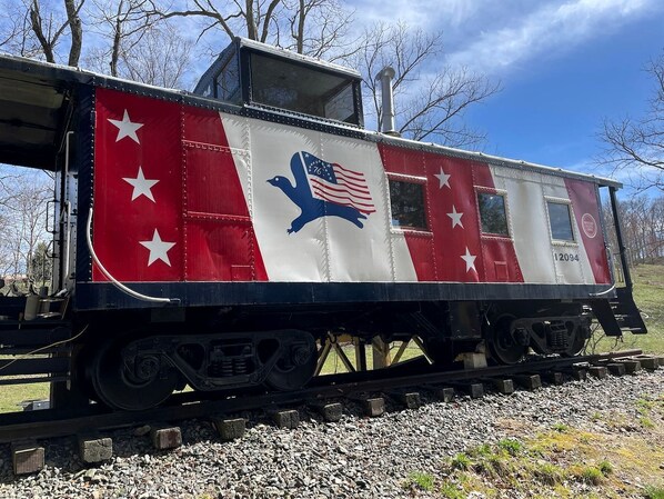 Un vagón de tren estacionado con un esquema de color rojo y blanco, estrellas y el emblema de un águila.