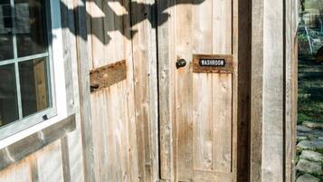 A wooden door with a 'WASHROOM' sign, a window, and a wooden deck with a doormat.