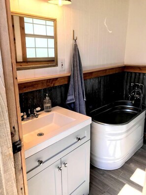 A bathroom with a white sink, a mirror, a towel rack, and a bathtub.