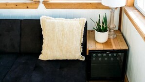 A cozy room with a black sofa, a white lamp, a potted plant, and a window with curtains.