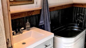 Ein Badezimmer mit einem weißen Waschbecken, einem Spiegel, einem Handtuchhalter und einer Badewanne.