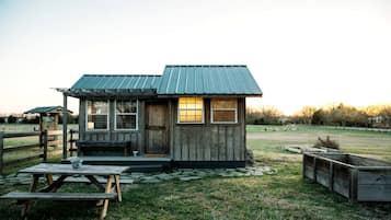 A rustic wooden cabin with a metal roof, a porch, and a picnic table.