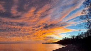 A beach with a curved shoreline, trees, and a distant landmass. - Cozy Tiny Cabin - Off-Grid Experience with Sled Dogs Year 'round in Minnesota (Grand Marais)