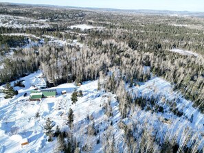 Paisatge cobert de neu amb un conjunt d'edificis, diverses construccions envoltades per un bosc dens.