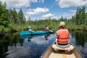 Dues canoes sobre un riu tranquil envoltat per un bosc dens.
