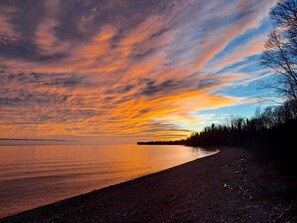 A beach with a curved shoreline, trees, and a distant landmass. - Cozy Tiny Cabin - Off-Grid Experience with Sled Dogs Year 'round in Minnesota (Grand Marais)