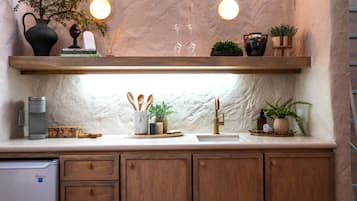 A kitchen with wooden cabinets, a marble countertop, a built-in sink, and a shelf with decorative items.