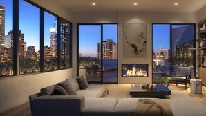Un salon moderne avec un canapé, une table basse et une cheminée. De grandes fenêtres offrent une vue sur le paysage urbain.