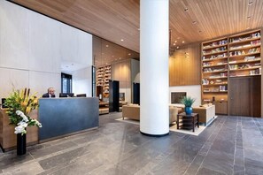 A modern lobby with a reception desk, seating area, and bookshelves. - Walkable 1BR nr Park Ave & Grand Central (New York)