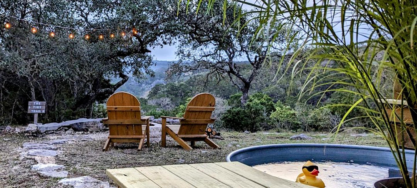 Two wooden Adirondack chairs, a small pool, and a sign indicating a trail.
