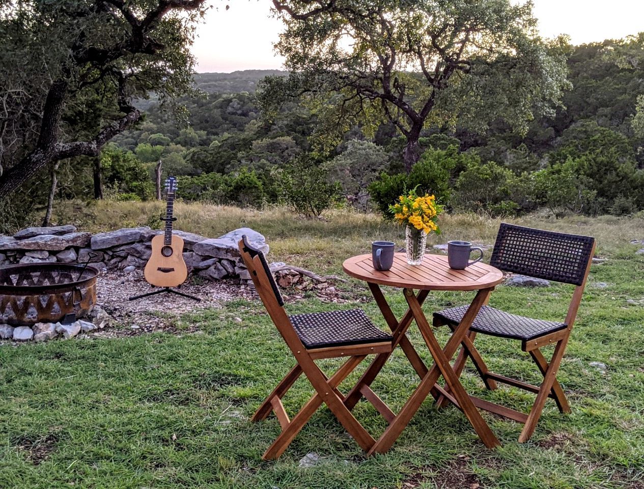 An outdoor seating area with a guitar, a fire pit, and a table with chairs.