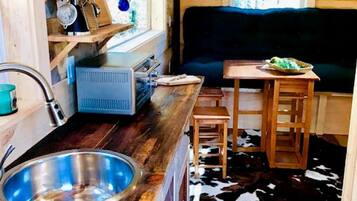 A compact kitchen with a sink, wooden cabinets, a window, and a cowhide rug.