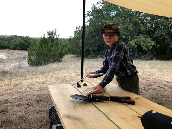 Una persona utilizando una herramienta sobre una mesa de madera al aire libre.