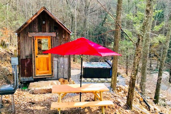 A rustic wooden cabin with a bench and picnic table, surrounded by trees. - Cozy and Rustic Cabin Rental in the Smokies for Romantic Getaways in Tennessee (Newport)