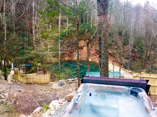 A hot tub in a wooded area with a wooden deck and a small shed. - Cozy and Rustic Cabin Rental in the Smokies for Romantic Getaways in Tennessee (Newport)