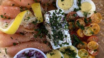 A glass plate with sliced salmon, hard-boiled eggs, cherry tomatoes, and a small bowl of red onion.