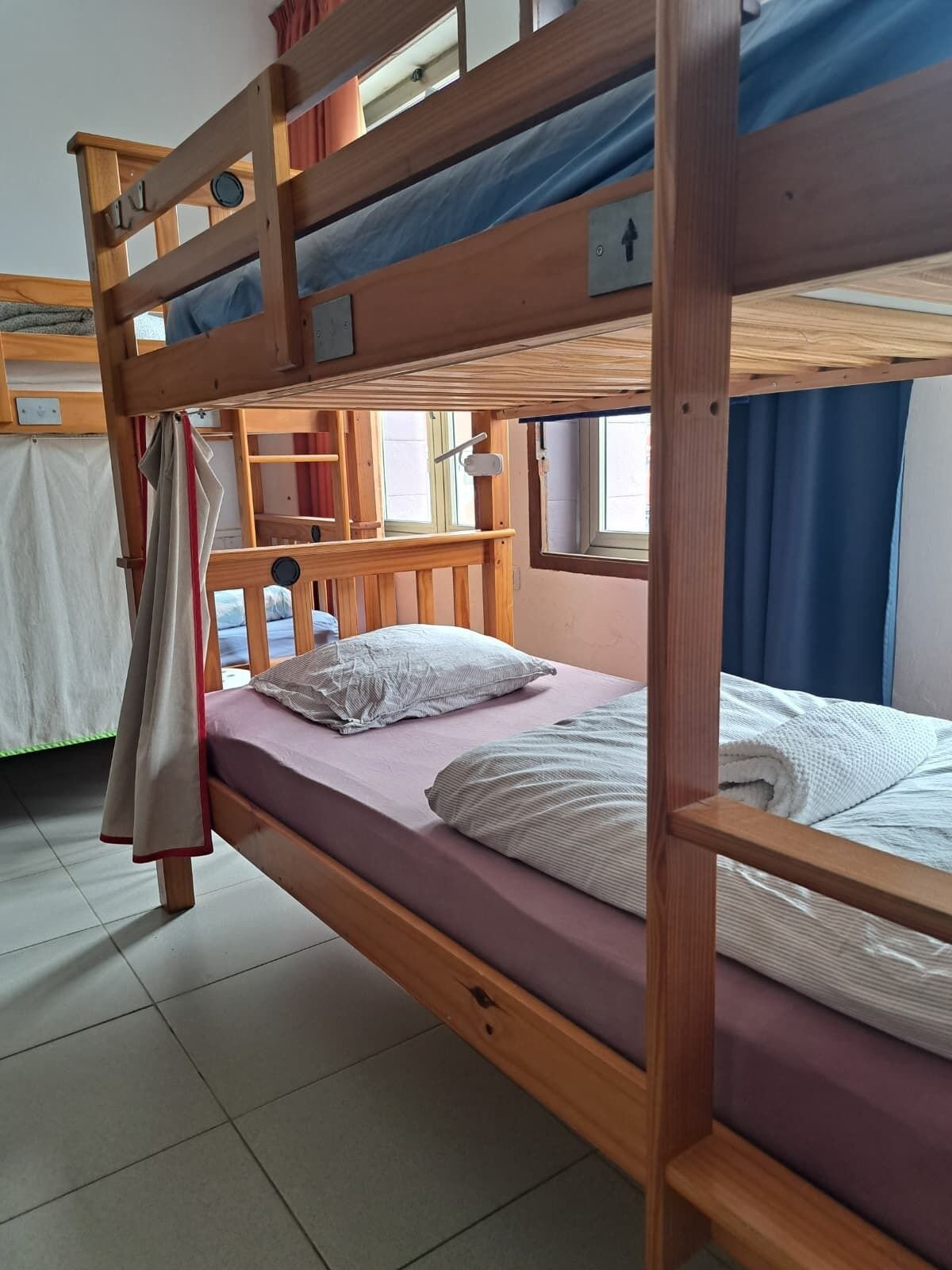 Una cama litera con estructura de madera, un colchón, almohadas y una colcha.