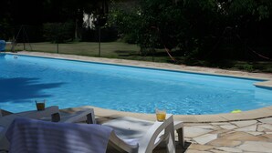 A swimming pool with lounge chairs and a glass of drink.