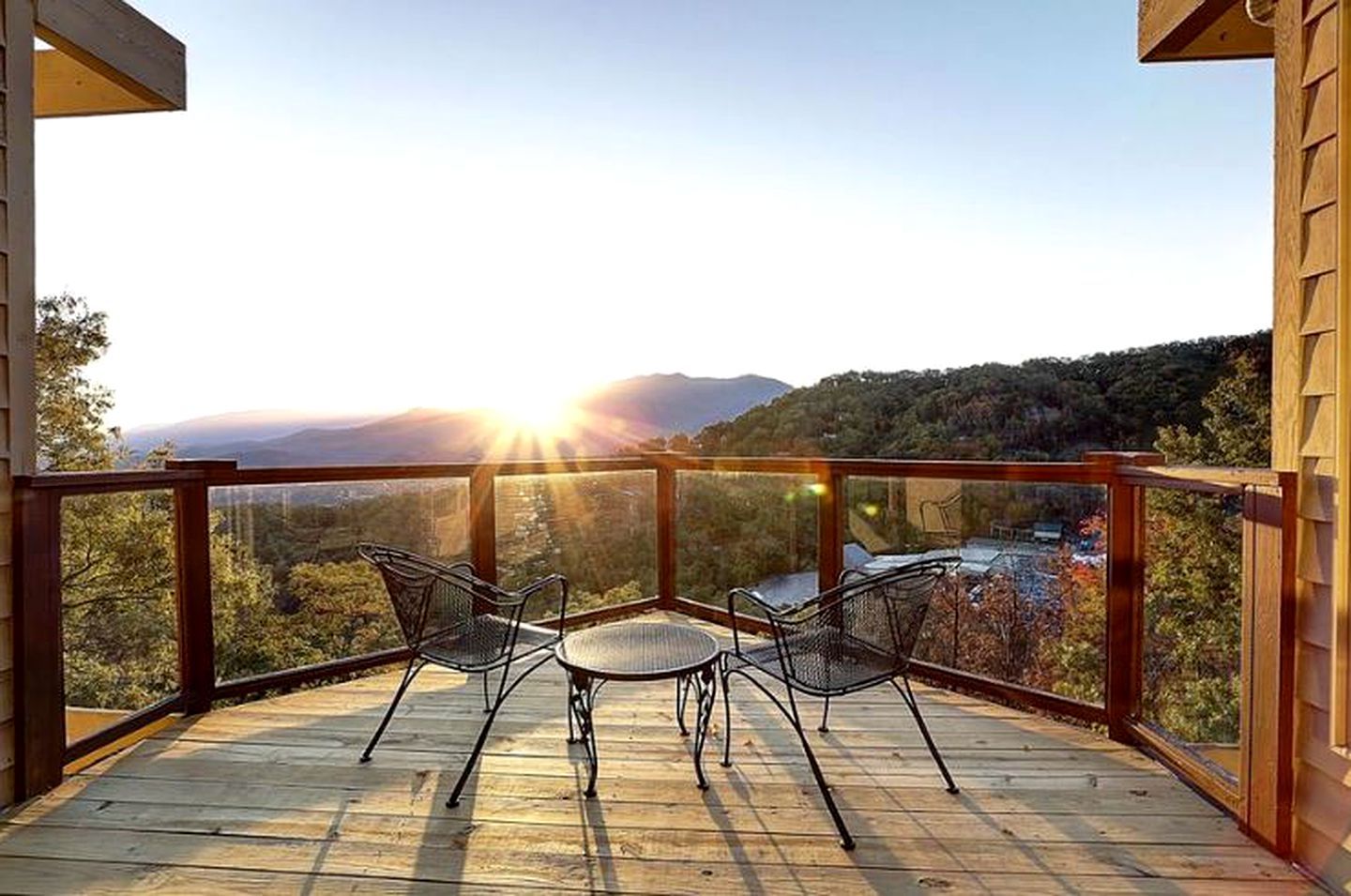 Un balcón con dos sillas y una mesa, con vista a un paisaje montañoso.