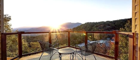Un balcón con dos sillas y una mesa, con vista a un paisaje montañoso.